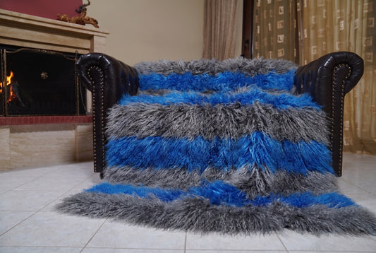 Mongolian Blanket Throw Grey Blue Striped — Wool Sheepskin spread across the leather sofa showing the whole charcoal grey and cobalt blue Mongolian wool surface — Greek craftsmanship, TatiFurs