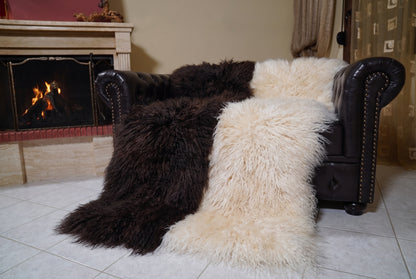 Mongolian Blanket Throw Dark Brown Cream Beige Two Tone angled view on the Chesterfield sofa with the fire glowing behind — espresso brown and cream beige full skin sheepskin, TatiFurs