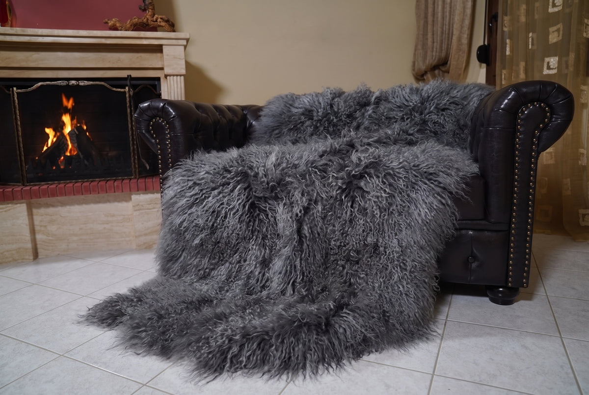Mongolian Blanket Throw Gray — Wool Sheepskin Full Skin angled view on the Chesterfield sofa with the fire glowing behind — grey full skin sheepskin, TatiFurs