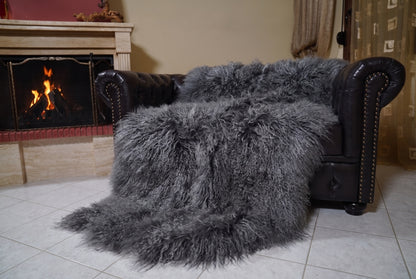 Mongolian Blanket Throw Gray — Wool Sheepskin Full Skin angled view on the Chesterfield sofa with the fire glowing behind — grey full skin sheepskin, TatiFurs