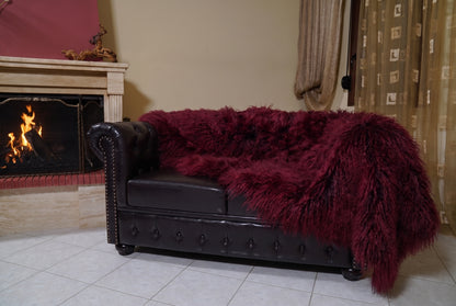 Mongolian Blanket Throw Burgundy — Wool Sheepskin Full Skin hanging from the sofa down to the travertine floor — deep oxblood burgundy Mongolian sheepskin throw, TatiFurs
