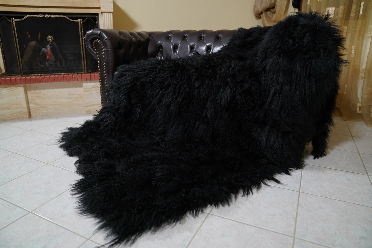 Wool Sheepskin Mongolian Blanket Throw Black - Tatifurs laid over the sofa arm and seat from the side, black Tibetan lamb fur falling to the floor — handmade in Greece