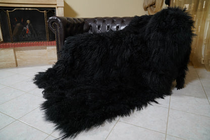 Wool Sheepskin Mongolian Blanket Throw Black - Tatifurs laid over the sofa arm and seat from the side, black Tibetan lamb fur falling to the floor — handmade in Greece