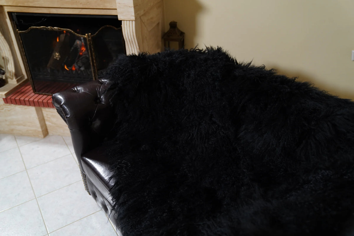 Wool Sheepskin Mongolian Blanket Throw Black - Tatifurs covering the seat and backrest of a leather sofa, top view of the thick black full skin wool pile by the fireplace