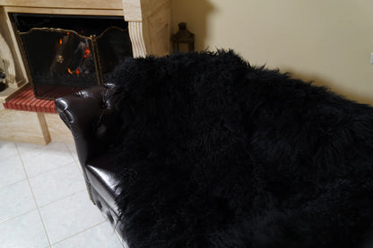 Wool Sheepskin Mongolian Blanket Throw Black - Tatifurs covering the seat and backrest of a leather sofa, top view of the thick black full skin wool pile by the fireplace