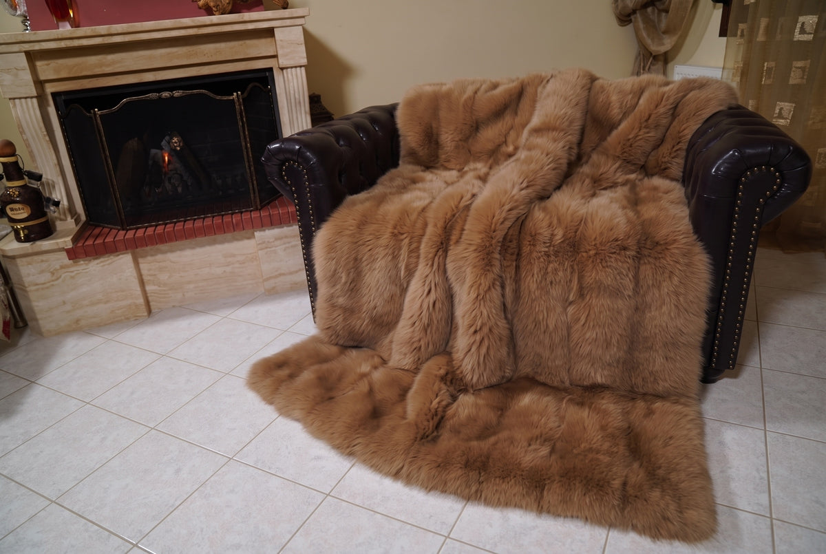 Fox Fur Blanket Throw Camel Brown — Full Skin Saga Furs covering the back and seat of the leather armchair, fireplace behind — the warm golden camel brown fox skins worked head to tail, TatiFurs