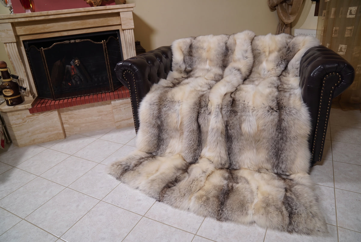 Fox Fur Blanket Throw Fawn Light — Full Skin Saga Furs covering the back and seat of the leather armchair, fireplace behind — the light fawn with a soft grey-brown line fox skins worked head to tail, TatiFurs