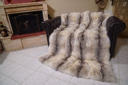Fox Fur Blanket Throw Fawn Light — Full Skin Saga Furs covering the back and seat of the leather armchair, fireplace behind — the light fawn with a soft grey-brown line fox skins worked head to tail, TatiFurs