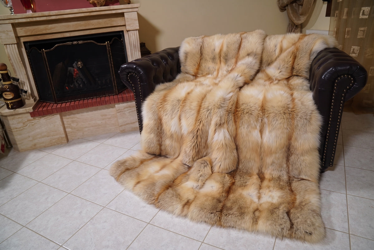Fox Fur Blanket Throw Golden Island — Full Skin Saga Furs covering the back and seat of the leather armchair, fireplace behind — the honey-gold Golden Island fox skins worked head to tail, TatiFurs