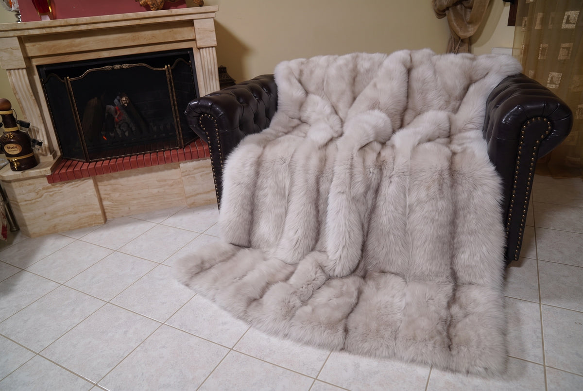 Fox Fur Blanket Throw Pastel Frost — Full Skin Saga Furs covering the back and seat of the leather armchair, fireplace behind — the soft greige with a taupe line fox skins worked head to tail, TatiFurs
