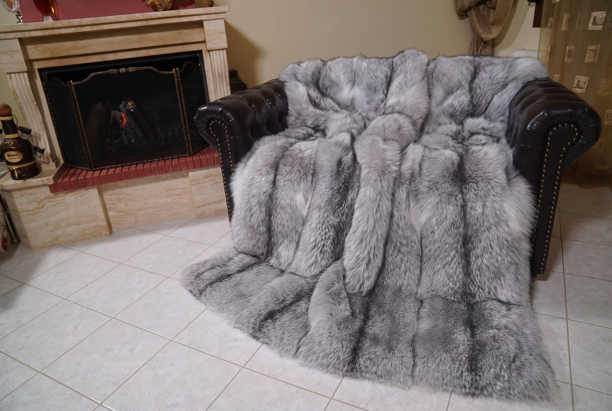 Fox Fur Blanket Throw Sapphire Frost — Full Skin Saga Furs covering the back and seat of the leather armchair, fireplace behind — the silver grey with white frosted tips and a charcoal line fox skins worked head to tail, TatiFurs