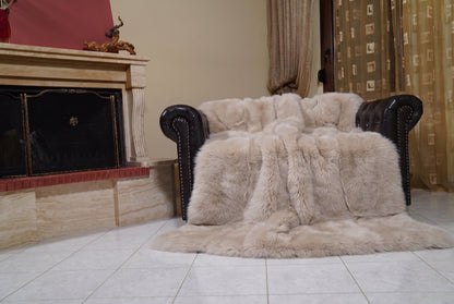 Fox Fur Blanket Throw Beige — Full Skin Saga Furs draped over a dark brown leather Chesterfield armchair beside the fireplace — full view of the warm sand beige full skin fox pelts, TatiFurs