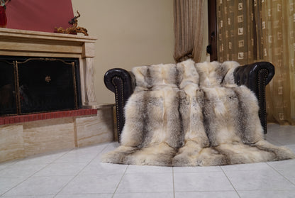 Fox Fur Blanket Throw Fawn Light — Full Skin Saga Furs draped over a dark brown leather Chesterfield armchair beside the fireplace — full view of the light fawn with a soft grey-brown line full skin fox pelts, TatiFurs