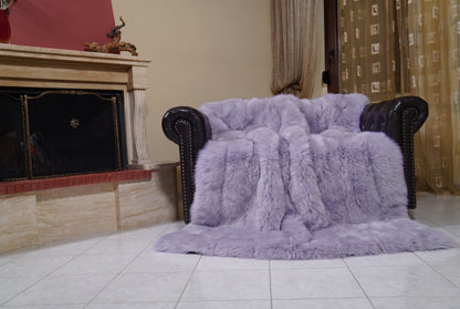 Fox Fur Blanket Throw Lavender Purple — Full Skin Saga Furs draped over a dark brown leather Chesterfield armchair beside the fireplace — full view of the soft lavender purple full skin fox pelts, TatiFurs
