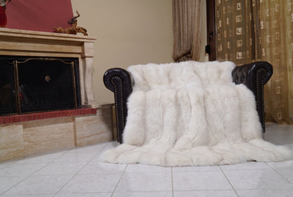 Fox Fur Blanket Throw Pearl Frost — Full Skin Saga Furs draped over a dark brown leather Chesterfield armchair beside the fireplace — full view of the pearl ivory with a soft champagne glow full skin fox pelts, TatiFurs