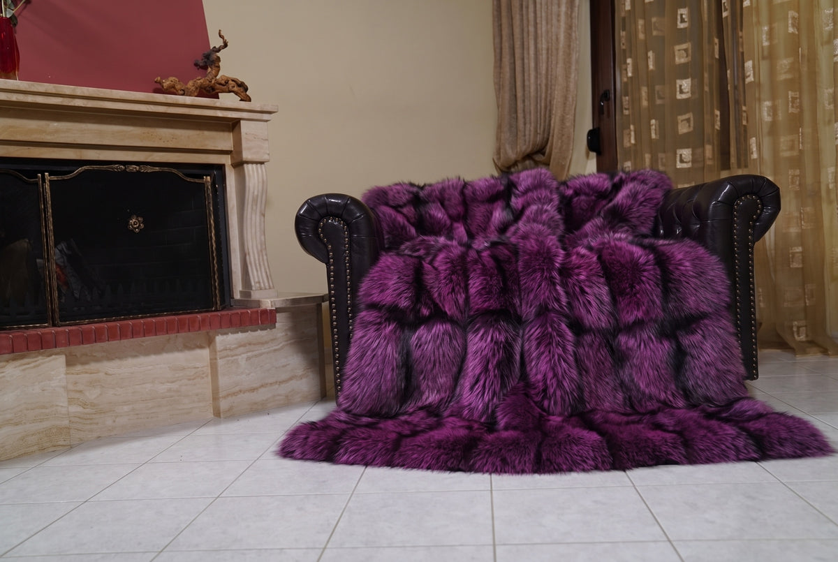 Fox Fur Blanket Throw Purple Silver — Full Skin Saga Furs draped over a dark brown leather Chesterfield armchair beside the fireplace — full view of the purple-tipped silver full skin fox pelts, TatiFurs