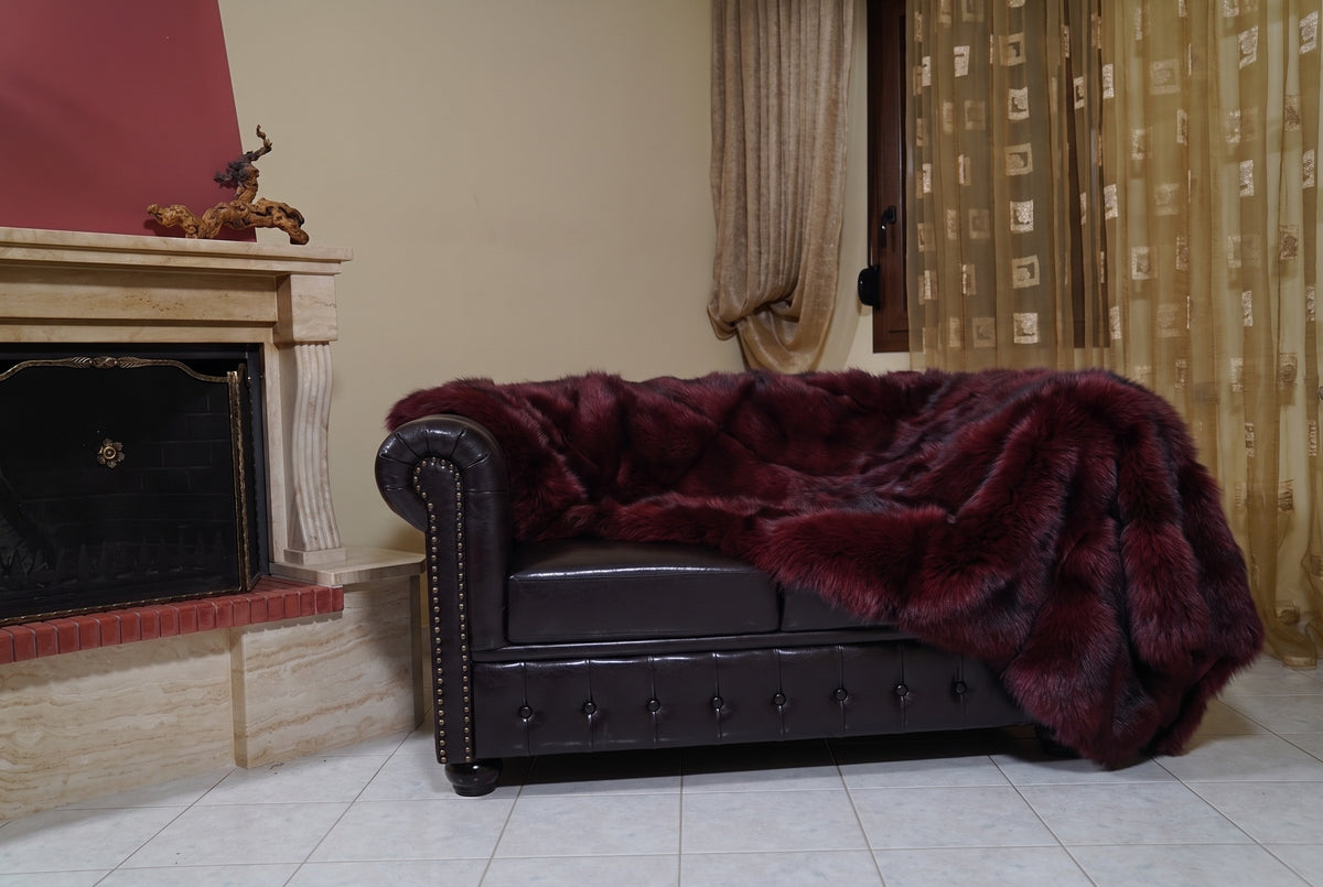 Fox Fur Blanket Throw Red Burgundy — Full Skin Saga Furs on the leather armchair in a fireplace living room with curtains — deep wine burgundy real fox fur throw, TatiFurs