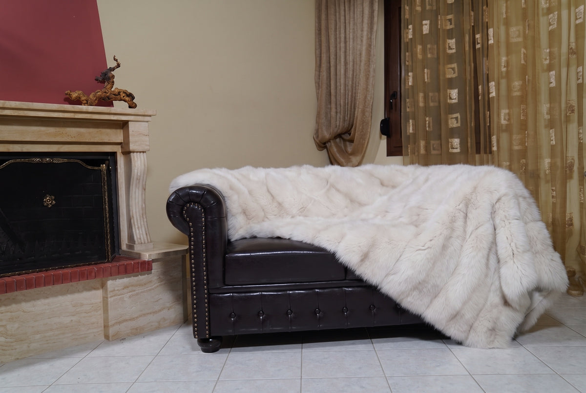 Fox Fur Blanket Throw Pearl Frost — Full Skin Saga Furs on the leather armchair in a fireplace living room with curtains — pearl ivory with a soft champagne glow real fox fur throw, TatiFurs