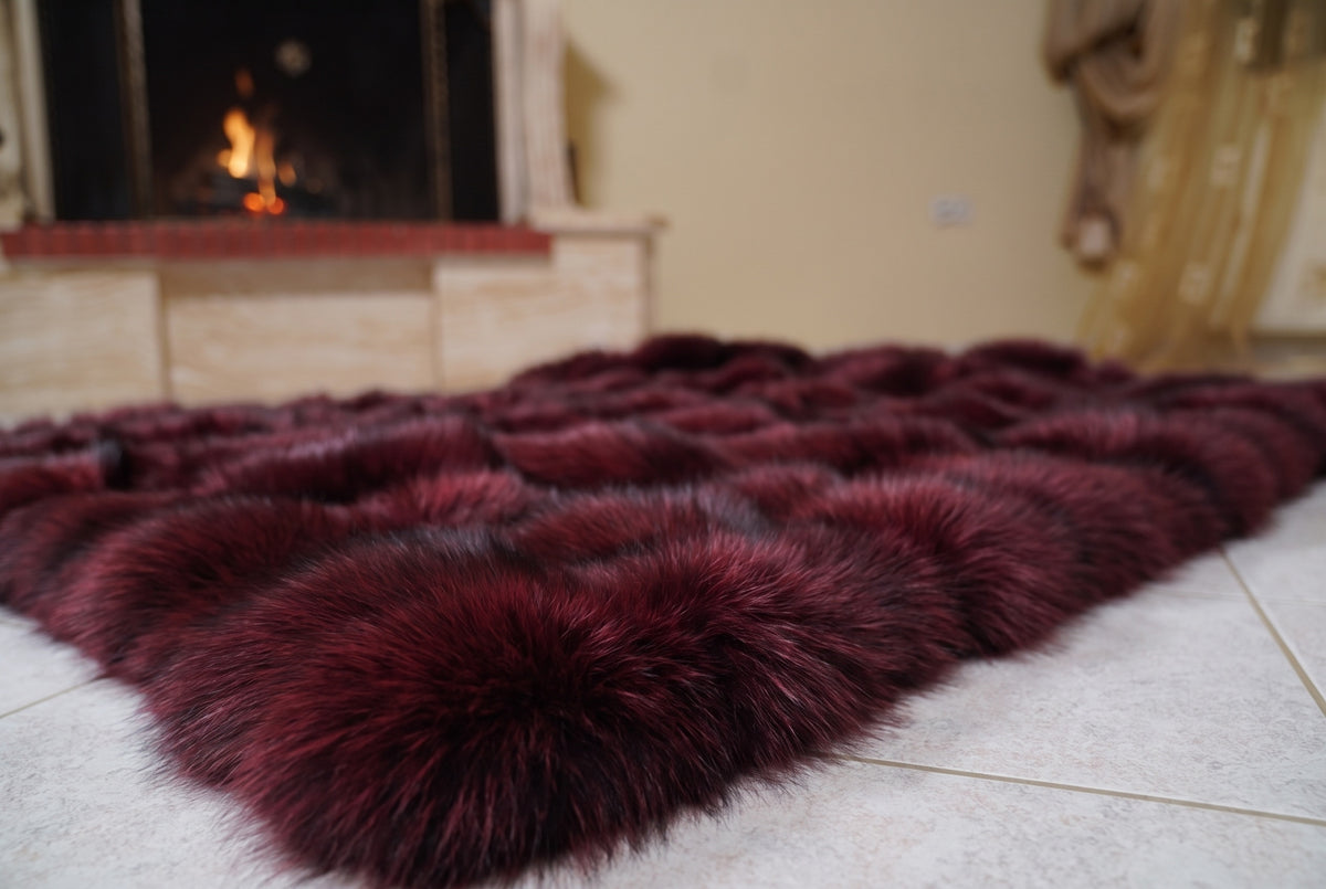 Fox Fur Blanket Throw Red Burgundy — Full Skin Saga Furs laid flat on the floor in front of the lit fireplace, low angle showing the deep wine burgundy fox pelt rows, TatiFurs