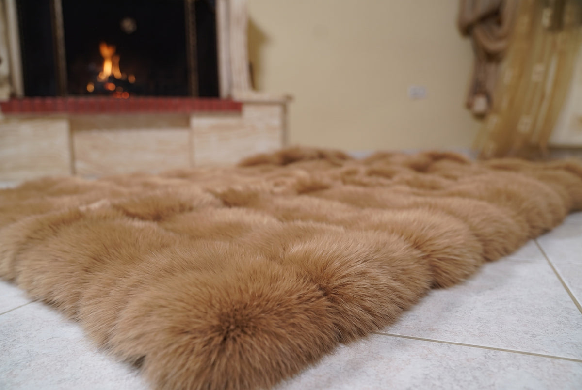 Fox Fur Blanket Throw Camel Brown — Full Skin Saga Furs laid flat on the floor in front of the lit fireplace, low angle showing the warm golden camel brown fox pelt rows, TatiFurs