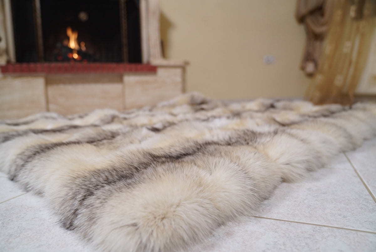 Fox Fur Blanket Throw Fawn Light — Full Skin Saga Furs laid flat on the floor in front of the lit fireplace, low angle showing the light fawn with a soft grey-brown line fox pelt rows, TatiFurs