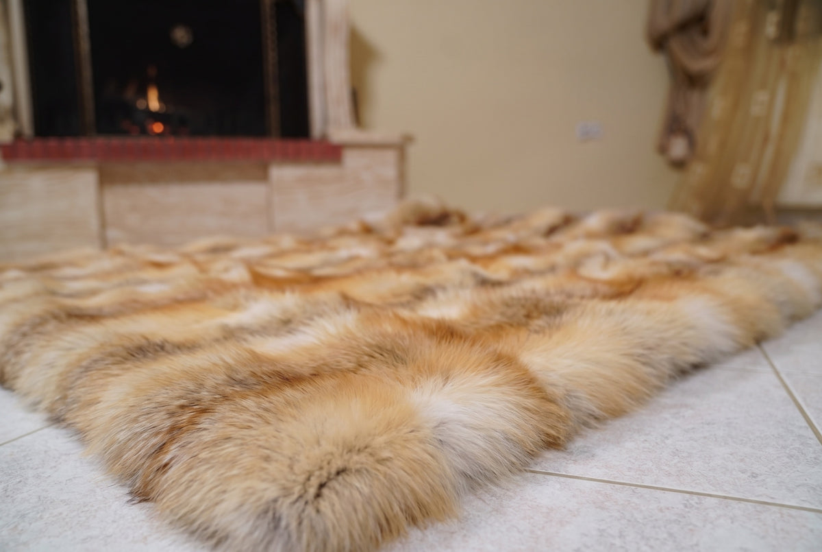Fox Fur Blanket Throw Golden Island — Full Skin Saga Furs laid flat on the floor in front of the lit fireplace, low angle showing the honey-gold Golden Island fox pelt rows, TatiFurs