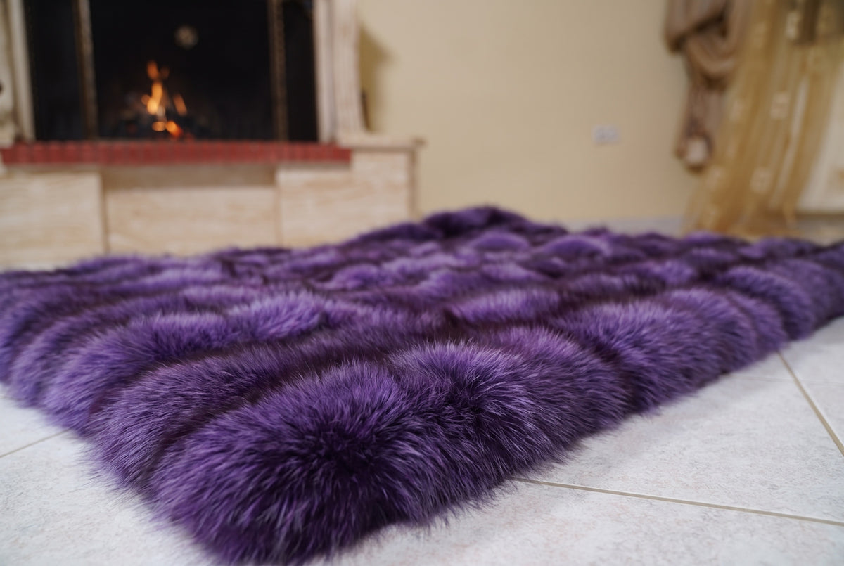 Fox Fur Blanket Throw Purple — Full Skin Saga Furs laid flat on the floor in front of the lit fireplace, low angle showing the rich violet purple fox pelt rows, TatiFurs