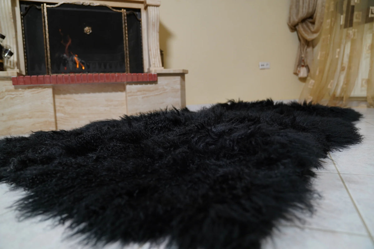 Wool Sheepskin Mongolian Blanket Throw Black - Tatifurs laid flat on the floor in front of the fireplace as a black sheepskin rug, showing the natural pelt outline