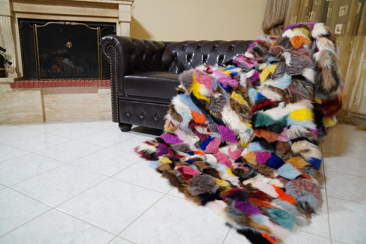fox fur blanket throw double sided colorful — full view draped over a Chesterfield sofa by the fireplace, multicolour fox in pink, purple, blue, yellow and orange — TatiFurs