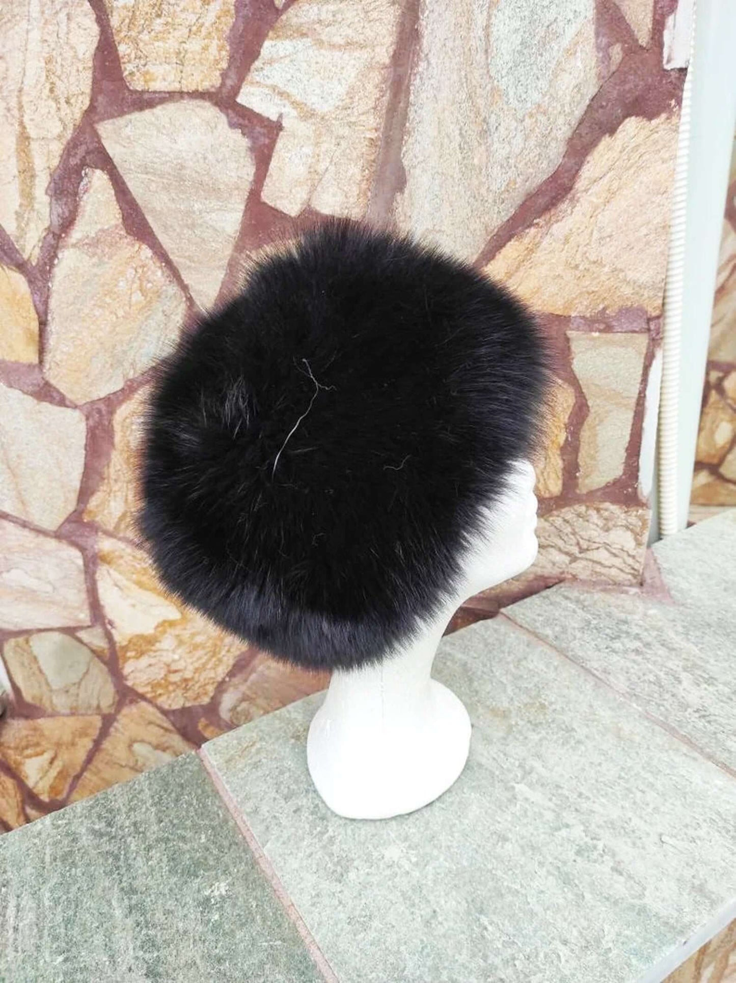 Fox Fur Hat Black - Tatifurs displayed on a mannequin against a stone background, showcasing its lush black fur texture.