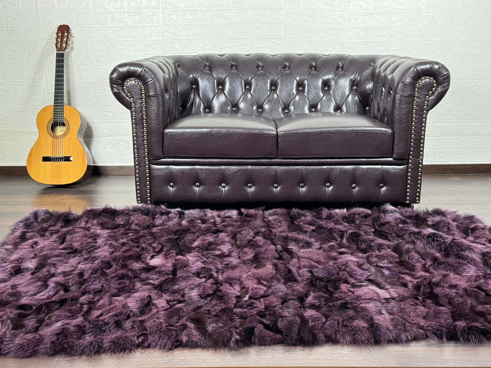 Luxury purple fox fur blanket with black details draped over a dark sofa showing rich regal tones and striking contrast

