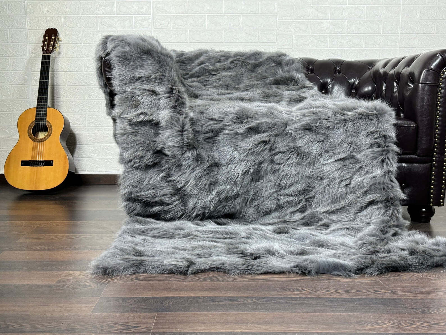 Fox Fur Blanket Throw Grey - Tatifurs displayed on a sofa, showcasing its luxurious soft texture and elegant gray color.