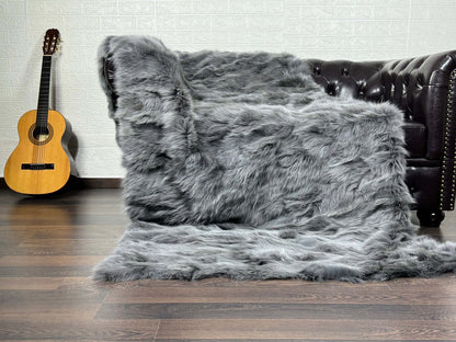 Fox Fur Blanket Throw Grey - Tatifurs displayed on a sofa, showcasing its luxurious soft texture and elegant gray color.