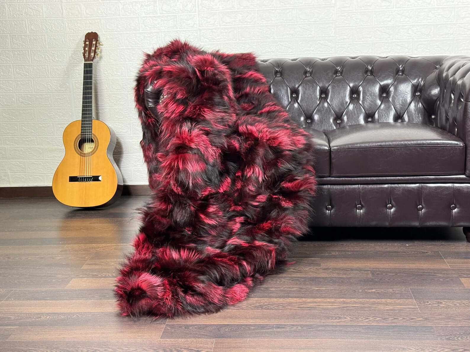 Fox Fur Blanket Throw Black Red - Tatifurs draped on a sofa with guitar in background, showcasing luxurious fur texture.