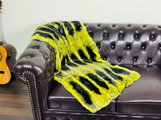 Rex Rabbit Blanket Throw Full Skin Yellow Black draped over a leather couch, showcasing vibrant yellow and black spots.