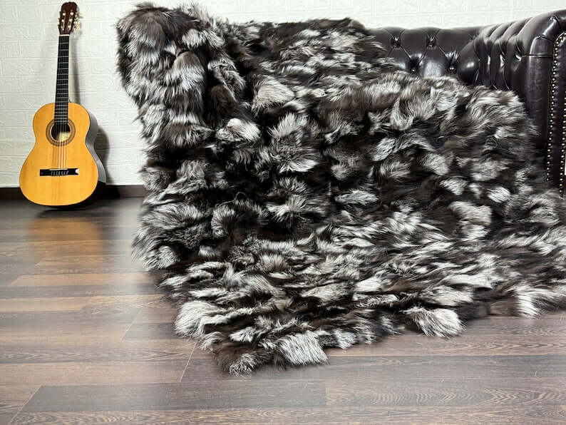 Fox Fur Blanket Throw Silver - Tatifurs draped over a couch with a guitar nearby, showcasing luxurious fur texture.