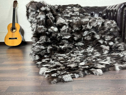 Fox Fur Blanket Throw Silver - Tatifurs draped over a couch with a guitar nearby, showcasing luxurious fur texture.