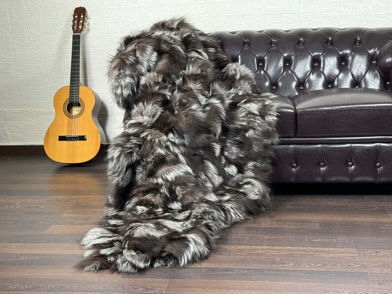 Fox Fur Blanket Throw Silver - Tatifurs draped over a couch with a guitar in the background, showcasing its luxurious texture.
