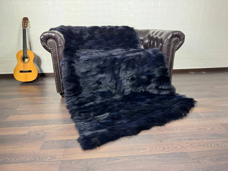 Fox Fur Blanket Throw Blue Black - Tatifurs draped on a couch, showcasing its luxurious texture and rich color.