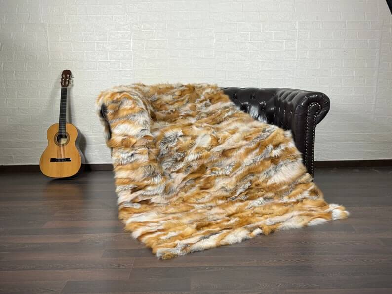 Fox Fur Blanket Throw Red Canadian - Tatifurs displayed on a couch with a guitar in the background.
