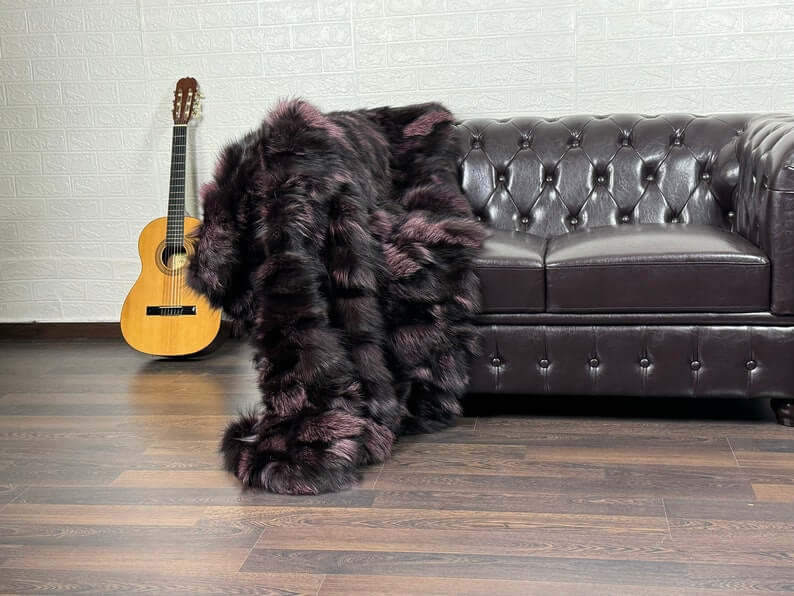 Fox Fur Blanket Throw Black Purple - Tatifurs draped over a sofa with guitar, showcasing luxurious black and purple fur.