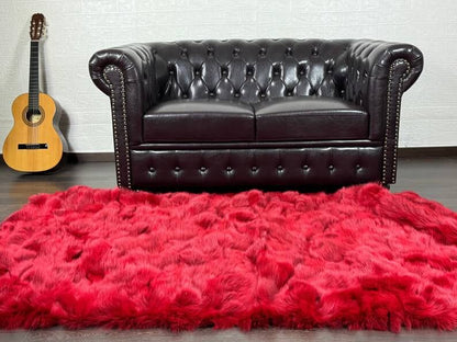 Fox Fur Blanket Throw Red - Tatifurs displayed on a luxurious leather couch, enhancing the room's warmth and style.