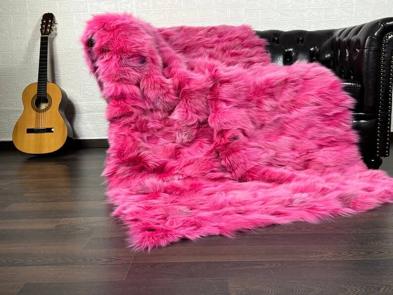 Fox Fur Blanket Throw Fuchsia - Tatifurs displayed on a sofa, showcasing its vibrant pink color and plush texture.
