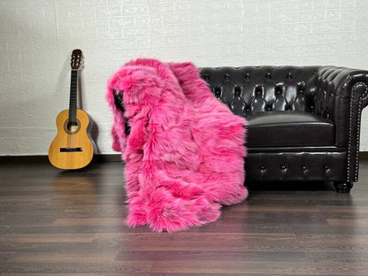 Fox Fur Blanket Throw Fuchsia - Tatifurs draped over a black leather couch, vibrant pink fur adds bold color to the room.