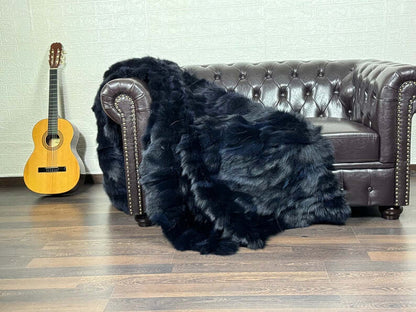 Fox Fur Blanket Throw Blue Black - Tatifurs draped over a luxurious couch with a guitar beside it.