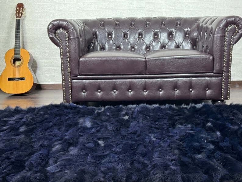 Fox Fur Blanket Throw Blue Black - Tatifurs on stylish living room floor with leather tufted sofa and guitar.