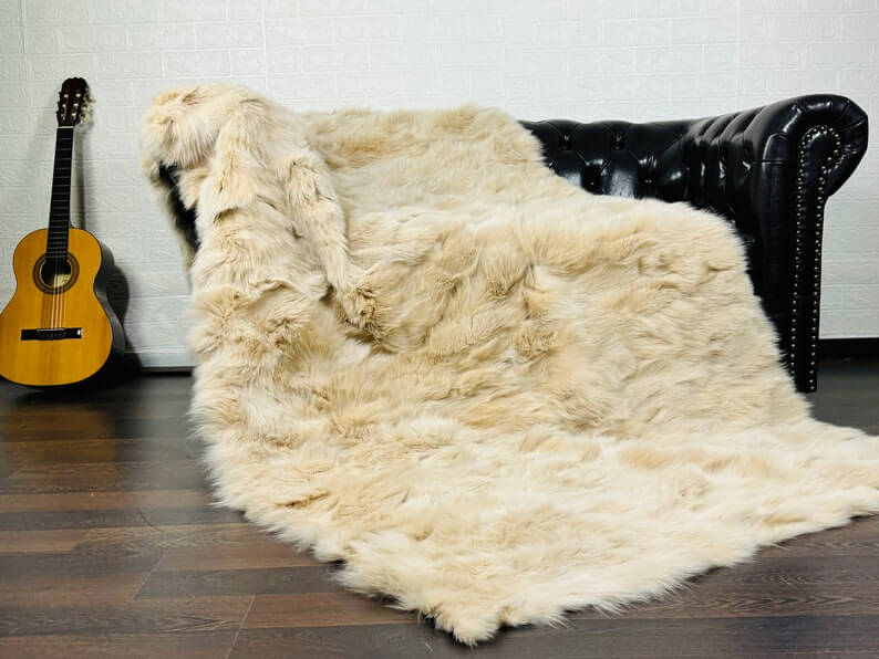 Fox Fur Blanket Throw Beige - Tatifurs on a black leather couch with an acoustic guitar.