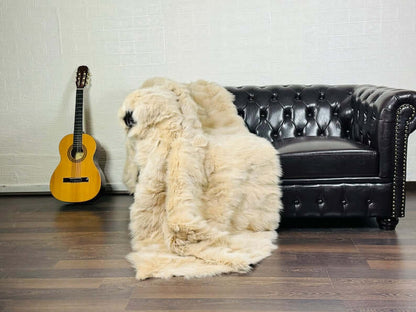 Fox Fur Blanket Throw Beige - Tatifurs draped over a leather couch with a guitar in the background.