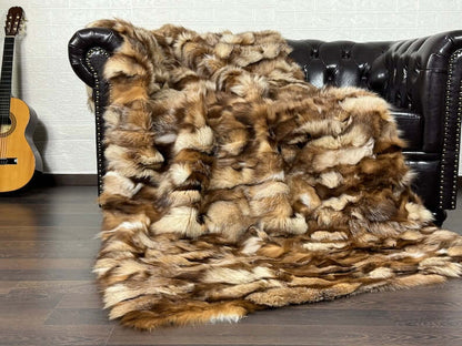 Fox Fur Blanket Throw Crystal Natural - Tatifurs draped on a leather sofa, showcasing its luxurious texture and colors.