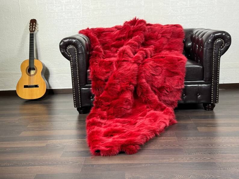Fox Fur Blanket Throw Red - Tatifurs draped over a couch, showcasing its vibrant color and luxurious texture.